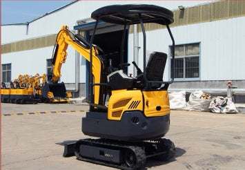 Side view of the JDSCT-16 mini excavator in yellow and black, parked outside a warehouse.